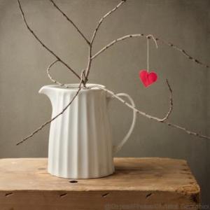 Paper heart hanging on tree branch in white jug