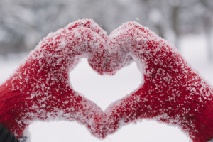 Woman making heart symbol with snowy hands