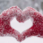 Woman making heart symbol with snowy hands